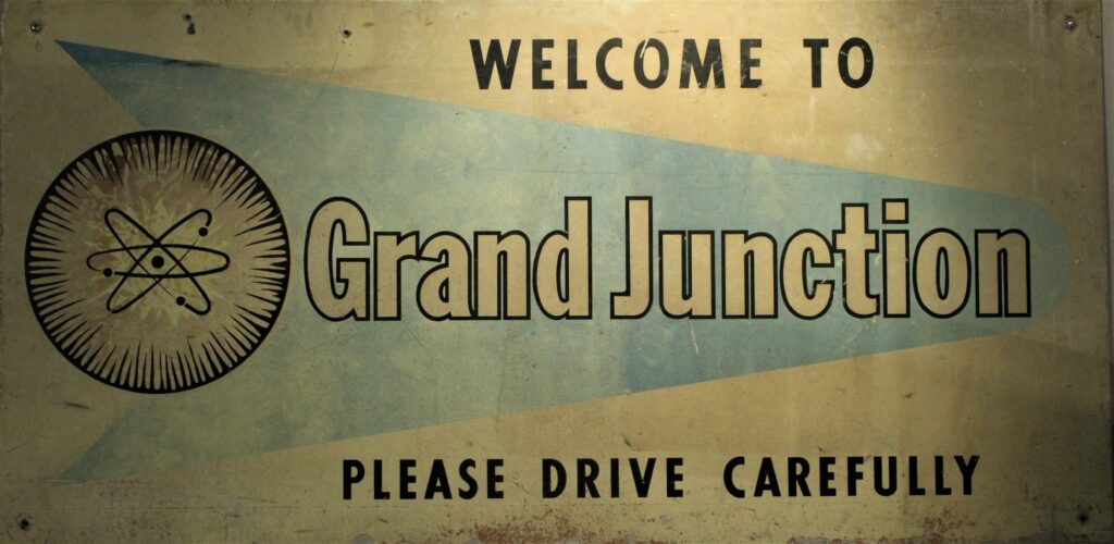 Image of sign saying Welcome to Grand Junction, with an atomic symbol on it. 