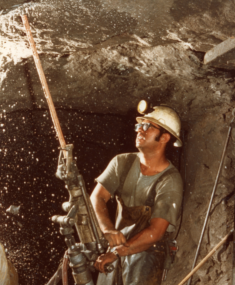 A man in a hard hat drills into rocks